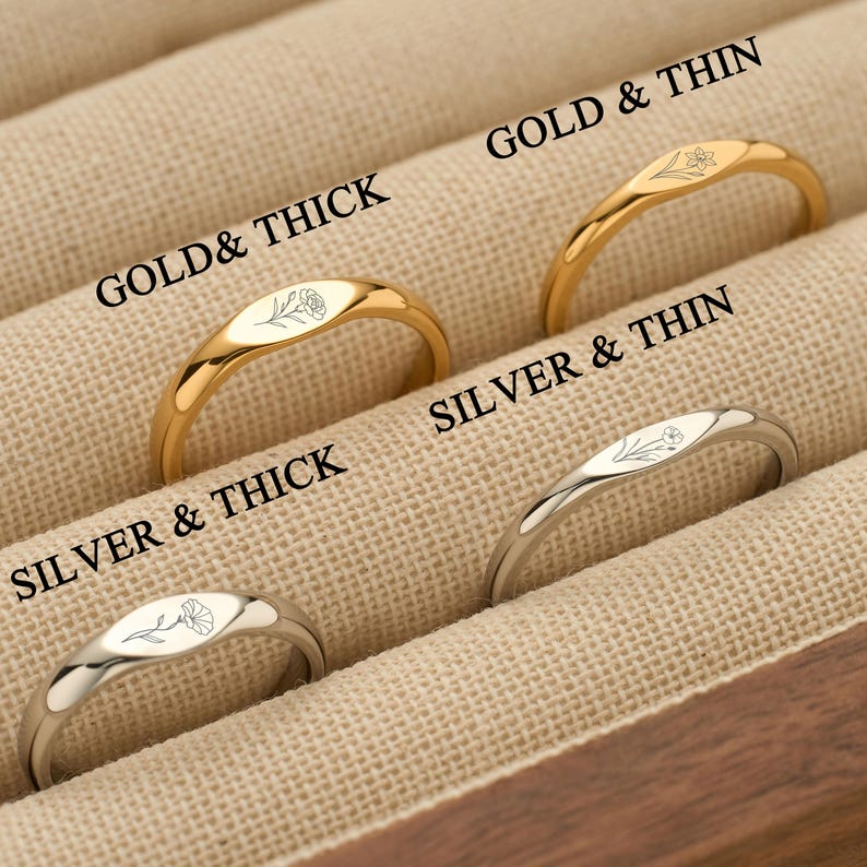 May include: Four rings displayed in a case. Two are gold, labelled "Gold & Thick" and "Gold & Thin". The other two are silver, labelled "Silver & Thick" and "Silver & Thin". Each ring features a floral design.