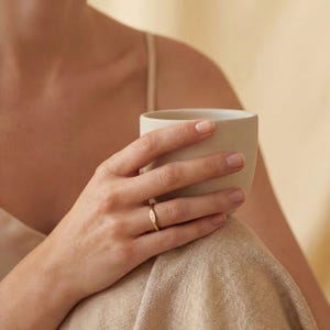 以下が含まれることがあります： つや消し仕上げの、斑点模様のセラミックマグカップ3個セット。マグカップはクリーム色、ライトグレー、ダークグレーの3色です。各マグカップはシンプルでミニマルなデザインで、丸みを帯びたハンドルが付いています。