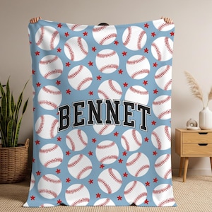 May include: A light blue fleece blanket featuring a repeating pattern of white baseballs with red stitching and small red stars. The name BENNET is printed in the center in a large, bold, black varsity-style font with a white outline.