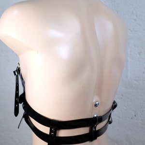 Product shot of a 2 story chest harness made from black PVC with high quality steel buckles and rivets showing close up details of the item