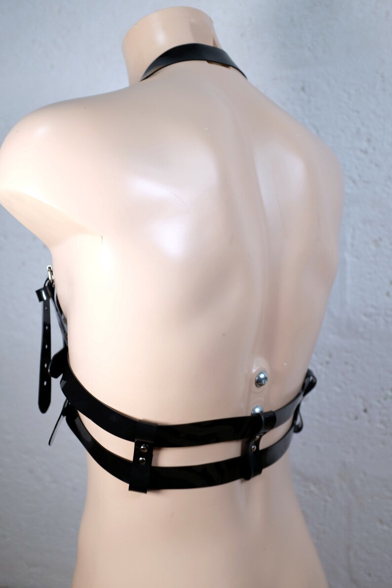 Product shot of a 2 story chest harness made from black PVC with high quality steel buckles and rivets showing close up details of the item