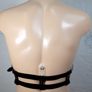 Product shot of a 2 story chest harness made from black PVC with high quality steel buckles and rivets showing close up details of the item