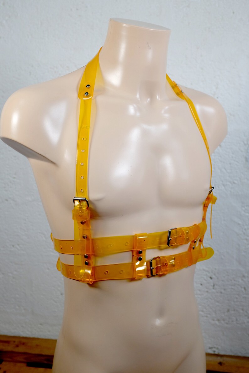 Product shot of a 2 story chest harness made from yellow transparent PVC with high quality steel buckles and rivets showing close up details of the item