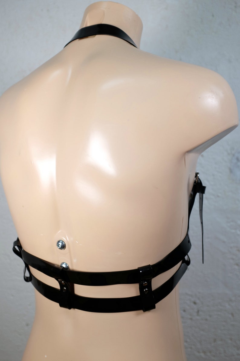 Product shot of a 2 story chest harness made from black PVC with high quality steel buckles and rivets showing close up details of the item