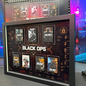 Peut inclure: Un cadre Call of Duty Black Ops Legacy Collection présentant sept jaquettes de jeux de 2010 à 2025. Le cadre noir contient un fond sombre avec des lignes orange rappelant des circuits, des portraits de personnages et le texte Black Ops.