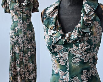 May include: A long green maxi dress with a floral print and a ruffled neckline. The dress has a button-up front and short sleeves.