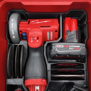 May include: A red and black power tool set, neatly organized within a red storage case. The set includes a red angle grinder, a battery, and several cutting discs. The case has black compartments to hold each tool securely.
