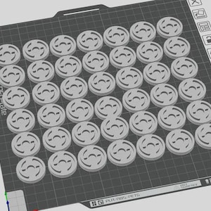 May include: A 3D-printed array of small, circular, light gray objects with a stylized design, arranged on a dark gray textured surface. The objects are evenly spaced and appear to be components or parts. The image is taken from an overhead perspective.