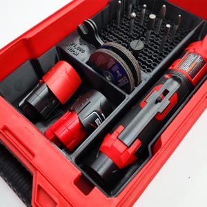 May include: A red and black tool organiser containing a rotary tool, grinding discs, drill bits, and two batteries. The organiser has the text "21,000 RPM". The accessories are neatly arranged within the black compartments.
