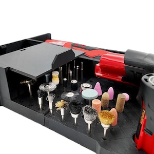 Puede incluir: Un kit de herramientas rotativas negro con una herramienta eléctrica roja y negra. El kit incluye varias puntas de esmerilado y pulido, incluyendo cepillos, tambores de lijado y piedras de esmerilado. Las puntas están en una caja de almacenamiento negra.