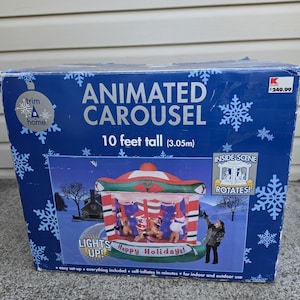 May include: A blue cardboard box for a 10 feet tall animated carousel inflatable decoration. The box features white snowflake patterns, the text "ANIMATED CAROUSEL", and an image of a rotating holiday carousel with figures.