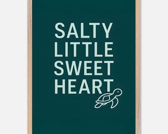 May include: A framed art print with the words "SALTY LITTLE SWEET HEART" in white, with a white turtle illustration on a dark teal background. The frame is a light wood color.