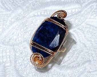 May include: A gold wire wrapped ring with a dark blue oval gemstone.