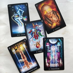 May include: Five tarot cards are displayed, each featuring detailed illustrations and text. The cards include "XVII. STAR," "0. FOOL," "V. FAITH," "HANGING MAN," and "II. PRIESTESS." The artwork showcases mystical figures, celestial elements, and symbolic imagery, with a dark background.