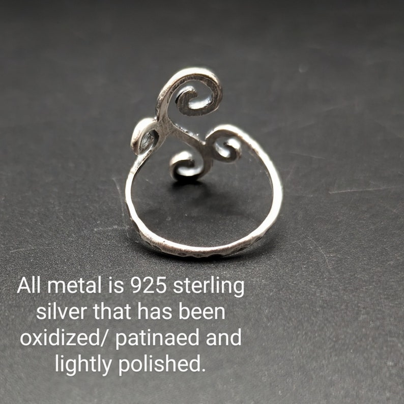 May include: Sterling silver ring with an oxidized finish. The ring features a swirling design with a textured band. The text in the image reads: "All metal is 925 sterling silver that has been oxidized/ patinaed and lightly polished."