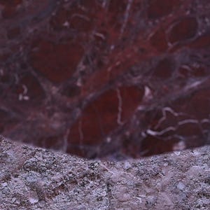 Peut inclure: Gros plan sur une surface de marbre rouge fonc&eacute; avec des veines blanches. Le marbre poli contraste avec une surface de pierre grise rugueuse. L'image montre une section du marbre.