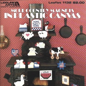 May include: A collection of country-themed plastic canvas magnets, including a house, pig, cow, and watermelon. The magnets are displayed on a decorative stove, with the text "MORE COUNTRY MAGNETS IN PLASTIC CANVAS" visible.