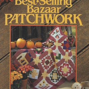May include: A book cover with the title "Best-Selling Bazaar Patchwork" in gold lettering. The cover features a patchwork quilt with star and geometric patterns, pumpkins, and flowers. The word "NEW" is in a green oval.