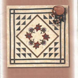 May include: A quilt pattern titled "Morning Dew" by Nancy Odom. The design features a central diamond with a floral wreath and surrounding geometric shapes. The quilt size is 34" x 34". The pattern is from Timid Thimble Creations.