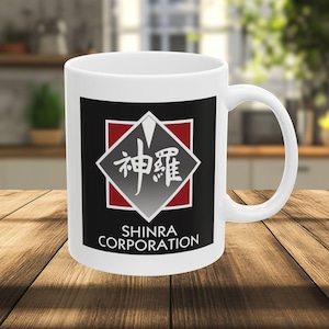 Puede incluir: Taza de cerámica blanca con un diseño gráfico en negro y rojo. El diseño presenta caracteres japoneses dentro de un rombo, con las palabras "SHINRA CORPORATION" debajo. La taza tiene un asa curvada.