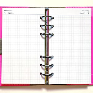 May include: Open planner with a bright pink cover and silver binder rings. The pages are white with a grid pattern and the dates "Wednesday 4 April" and "Thursday April 5" are printed at the top of the pages.