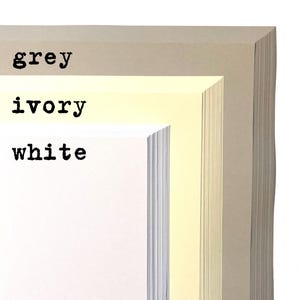 May include: Three stacks of paper in different colors: white, ivory, and grey. The paper is stacked in a way that shows the edges of each sheet.