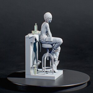 May include: A light gray 3D printed resin figurine of a person with short hair sitting on a tall stool at a bar counter. The figure wears pants and boots, with a bottle and glass on the counter. The base features the text HOBBY TEKA3D.
