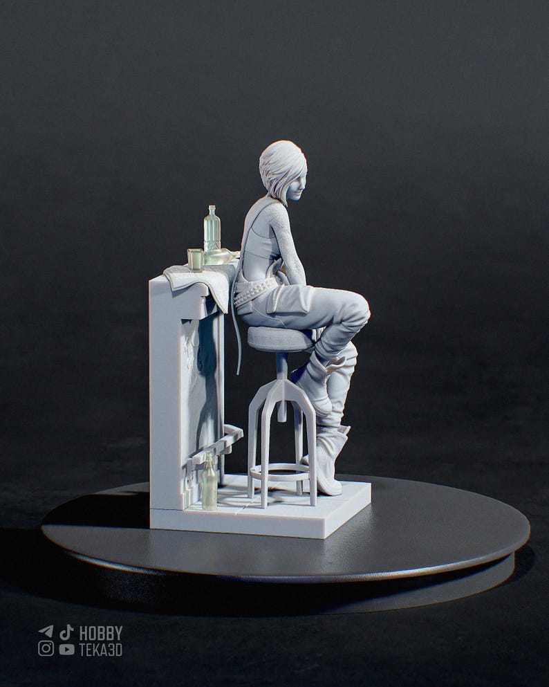 May include: A light gray 3D printed resin figurine of a person with short hair sitting on a tall stool at a bar counter. The figure wears pants and boots, with a bottle and glass on the counter. The base features the text HOBBY TEKA3D.