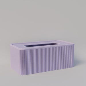 Può includere: Un portatovaglioli rettangolare lilla con un design a coste. La parte superiore presenta un'apertura lunga e stretta per l'erogazione dei fazzoletti. La scatola è di colore pieno e ha un'estetica minimalista.