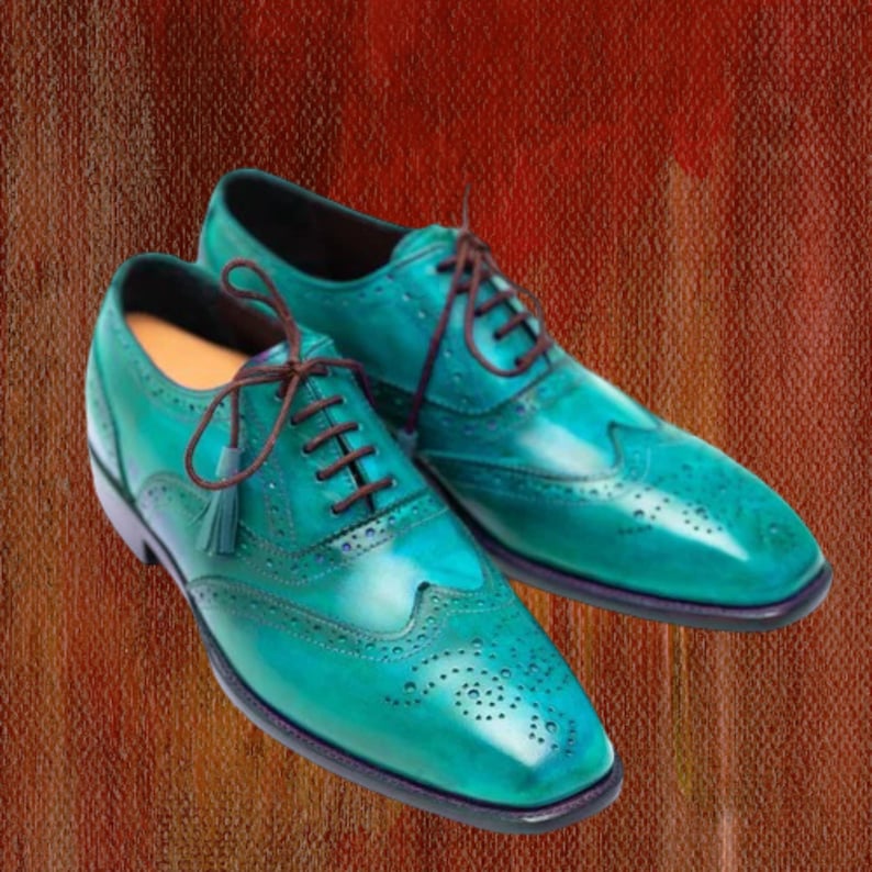 May include: A pair of teal leather dress shoes with brown laces and decorative perforations. The shoes have a classic wingtip design and a polished finish, perfect for formal occasions.