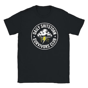 Puede incluir: Camiseta negra con un diseño circular blanco. El diseño presenta el texto "DAILY SHITSTORM SURVIVORS CLUB", una nube y rayos. Una camiseta casual y unisex.