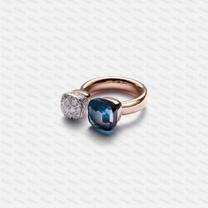 May include: A rose gold ring with two stones: a square cluster of diamonds and a teal-blue, cushion-cut gemstone. The ring has a polished band. The ring's design is simple.