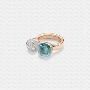 May include: A rose gold ring with two gemstone features. One is a cluster of small, clear diamonds, the other a square, light blue gemstone. The ring has a simple, polished band. The ring's design is elegant.