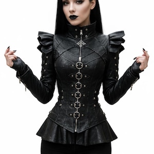 Puede incluir: Chaqueta negra de cuero sintético con cuello alto, cierre de cremallera y anillos plateados decorativos. La chaqueta presenta detalles de hombros con volantes y un bajo peplum. Prenda de moda gótica.