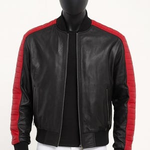 May include: Black leather bomber jacket with red shoulder and sleeve accents. The jacket features a ribbed collar, cuffs, and hem, and a front zipper closure. The sleeves have a quilted design. The jacket is displayed on a mannequin.