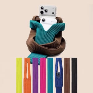 May include: A white smartphone is encased in a teal and brown knitted phone case, with a selection of colorful knitted straps in yellow, orange, purple, pink, teal, blue, brown, and black. The phone case is designed to be worn around the neck.