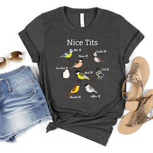 K&ouml;nnte beinhalten: Dunkelgraues T-Shirt mit dem Text "Nice Tits" und Illustrationen verschiedener Vogelarten. Dazu Jeansshorts, Sonnenbrille und Sandalen, was einen l&auml;ssigen, sommerlichen Look ergibt.