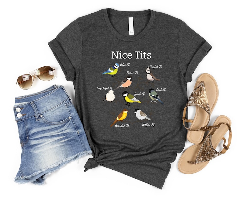 K&ouml;nnte beinhalten: Dunkelgraues T-Shirt mit dem Text "Nice Tits" und Illustrationen verschiedener Vogelarten. Dazu Jeansshorts, Sonnenbrille und Sandalen, was einen l&auml;ssigen, sommerlichen Look ergibt.