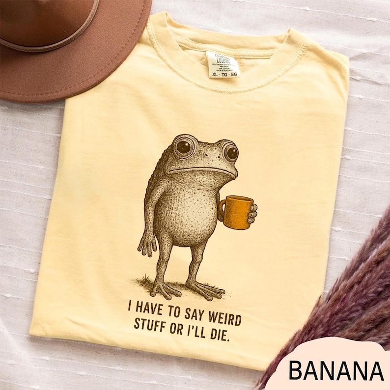 a yellow t-shirt with a frog graphic and text, along with a brown hat and a purple scarf.