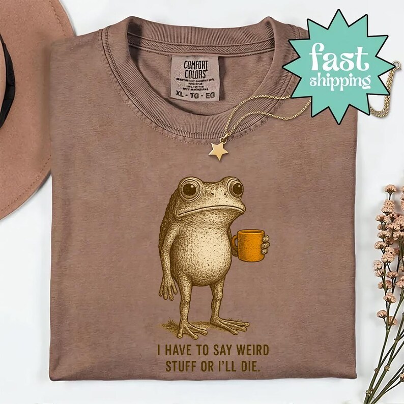 a brown t-shirt with a cartoon frog holding a coffee cup and the text "I HAVE TO SAY WEIRD STUFF OR ILL DIE."
