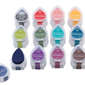 May include: A collection of twelve VersaMagic multi-surface chalk ink pads in various colors, including red, green, and blue. Each pad is teardrop-shaped and labeled with the ink color name and a product code. One ink pad is shown separately.