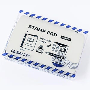 May include: A rectangular Sanby navy stamp pad in a clear plastic case with blue and white diagonal striped borders. The lid features black illustrations of a notebook, ink bottle, pen, and envelope with the text STAMP PAD, NAVY, and MY FAVORITE.