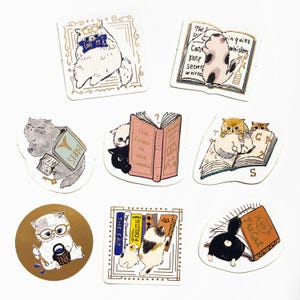 May include: A collection of eight die-cut stickers featuring illustrated cats interacting with books. The designs include cats reading, sitting on books, and holding ink, with text such as 'The Fairy in the Garden', 'The Cat', and 'Cats keep secrets'.