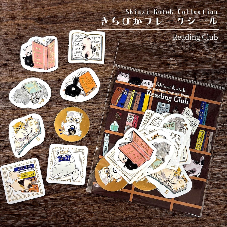 May include: A Shinzi Katoh Collection Reading Club sticker set featuring various illustrations of cats interacting with books. The set includes loose die-cut stickers and a clear plastic bag containing additional stickers, all with cat-themed designs.