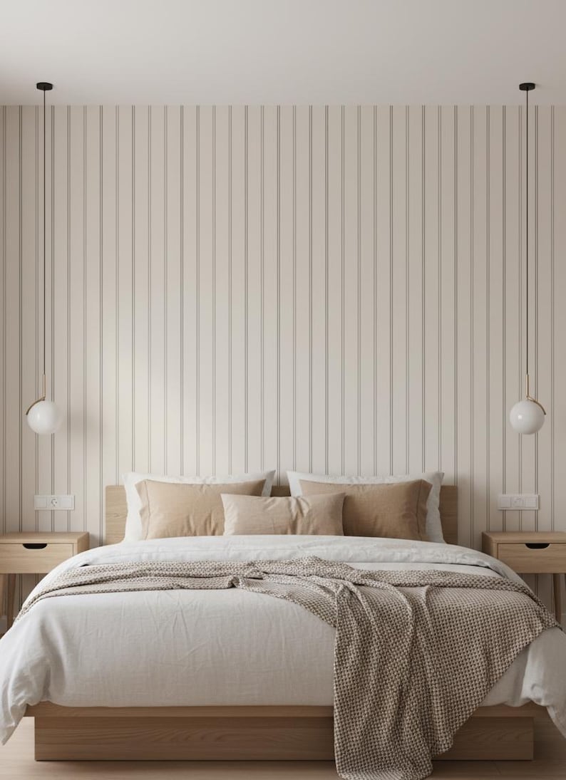 May include: A bedroom scene featuring a bed with a wooden frame, dressed in white linens and tan pillows. A woven throw blanket adds texture. Two spherical pendant lights hang above the bed. The wall is paneled with vertical, light-colored wood.