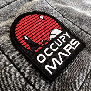 Könnte beinhalten: Ein gestickter schwarzer und weißer Aufnäher mit einer roten und weißen Sonnenuntergangsszene und dem Text "Occupy Mars".