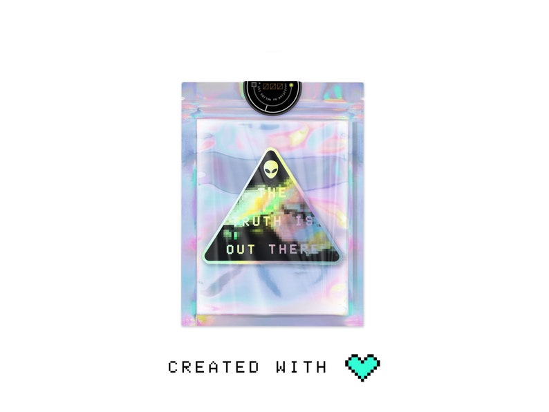 May include: A holographic sticker with a black triangle and the text "THE TRUTH IS OUT THERE" in a pixelated font. The sticker is on a white background.