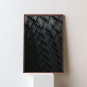 May include: A framed print featuring a close-up of a textured, dark gray pattern resembling overlapping scales. The artwork is encased in a brown wooden frame, creating a striking contrast against the neutral background.