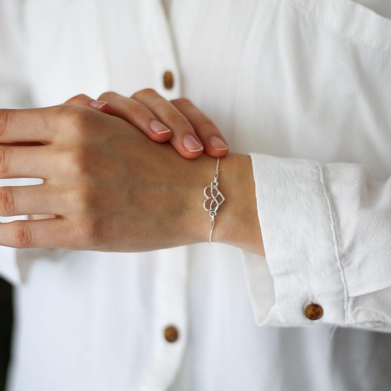 Puede incluir: Una delicada pulsera de cadena de plata con un dije central de coraz&oacute;n calado que integra un s&iacute;mbolo de infinito en su dise&ntilde;o. La pulsera se sujeta con una cadena fina de plata pulida que rodea la mu&ntilde;eca.