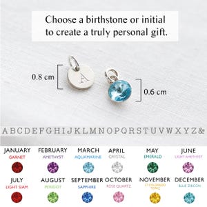 May include: Two small pendants are shown, one with the letter "A" engraved, measuring 0.8 cm, and another with a blue gemstone, 0.6 cm in size. The image includes a chart of birthstones and the alphabet. The text reads: Choose a birthstone or initial.
